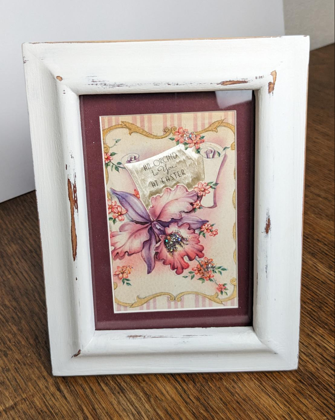 Distressed white frame showcases a vintage Easter card. 