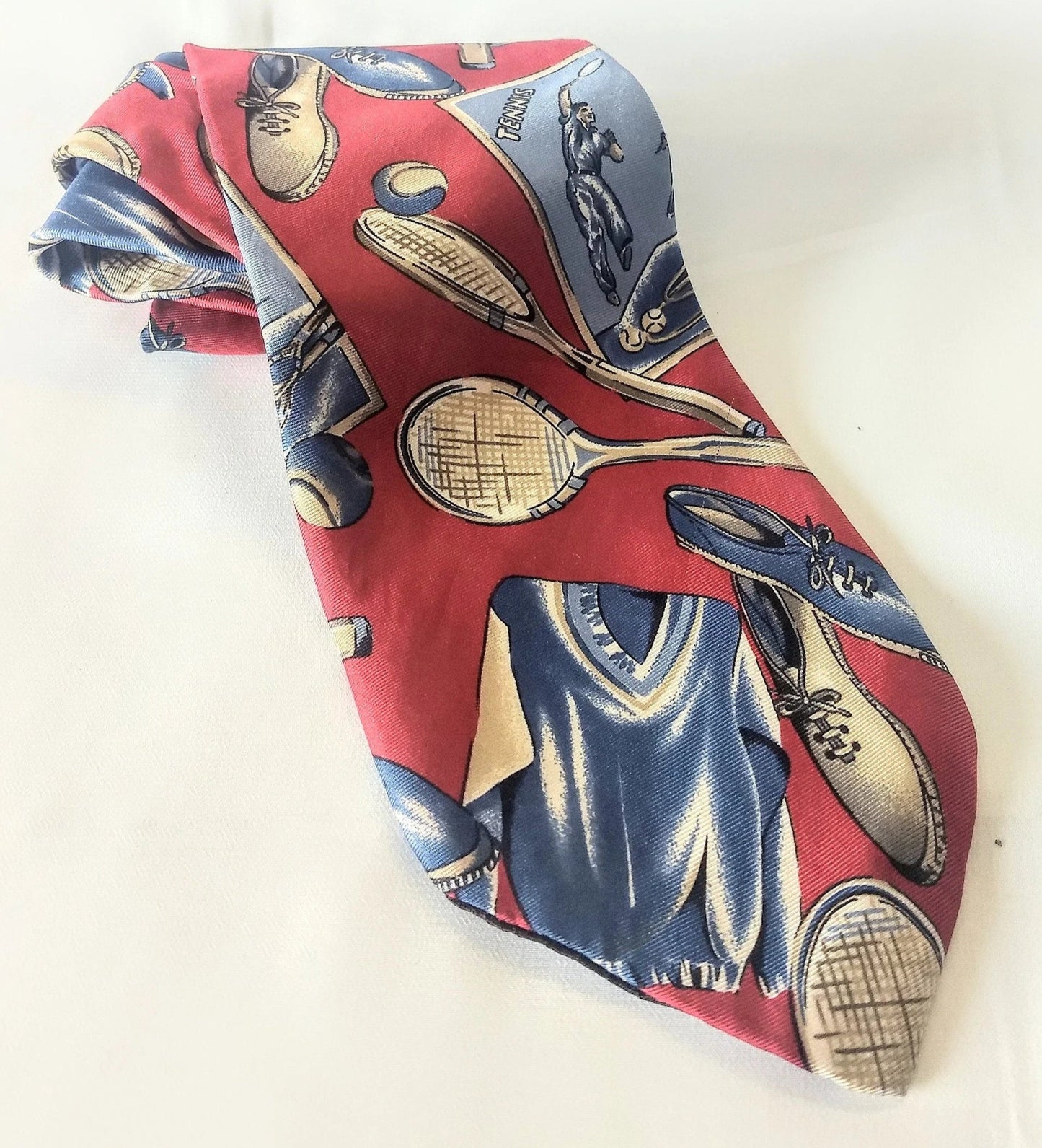 Red vintage necktie with blue tennis outfits, both blue and white tennis shoes, and white rackets. The tennis balls are both blue and white. There's also images of people playing tennis.